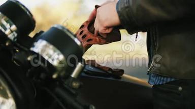 一个不可辨认的摩托车手，带着棕色的皮手套，戴着特殊的皮手套，<strong>坐在车上</strong>